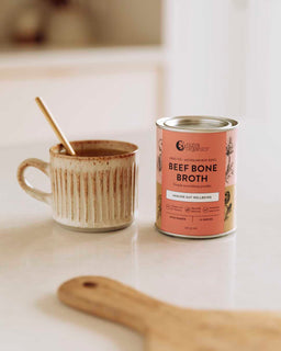 A mug of broth sits next to a tin of Nutra Organic's Beef Bone Broth miso ramen