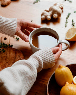  two hands reach out to pick up a mug of broth made from Beef bone broth concentrate lemon ginger ACV