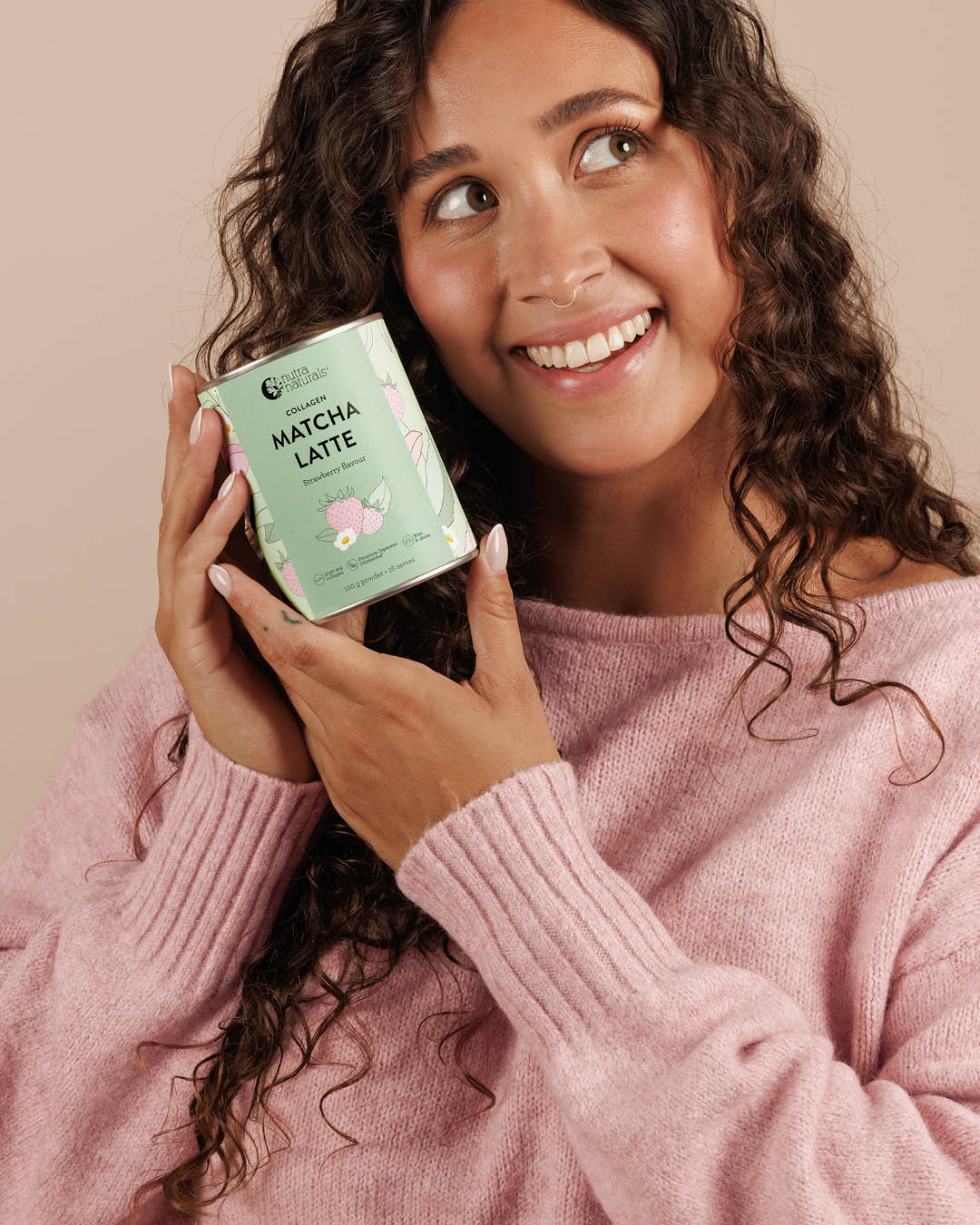 A woman holds a can of Collagen Strawberry Matcha Latte