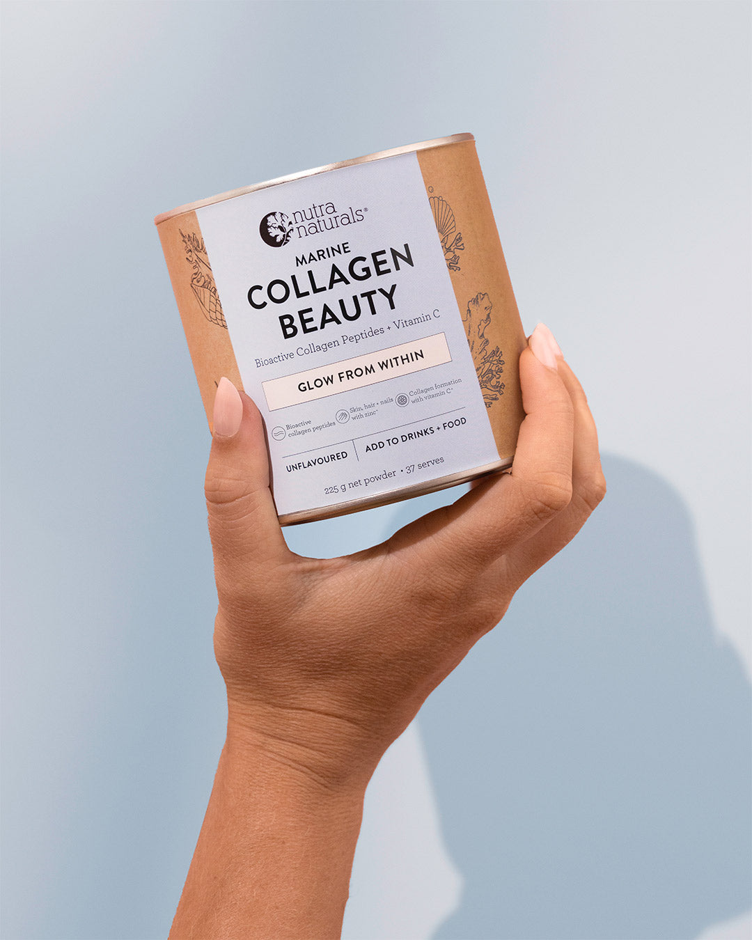 A hand holding a container of Nutra Naturals Marine Collagen Beauty powder against a soft light blue background.