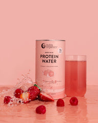 Protein Water Berry Bliss canister with a glass of water and berries on a pink background