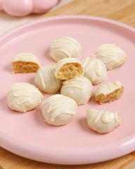 White chocolate truffles on a pink plate with a wooden surface underneath