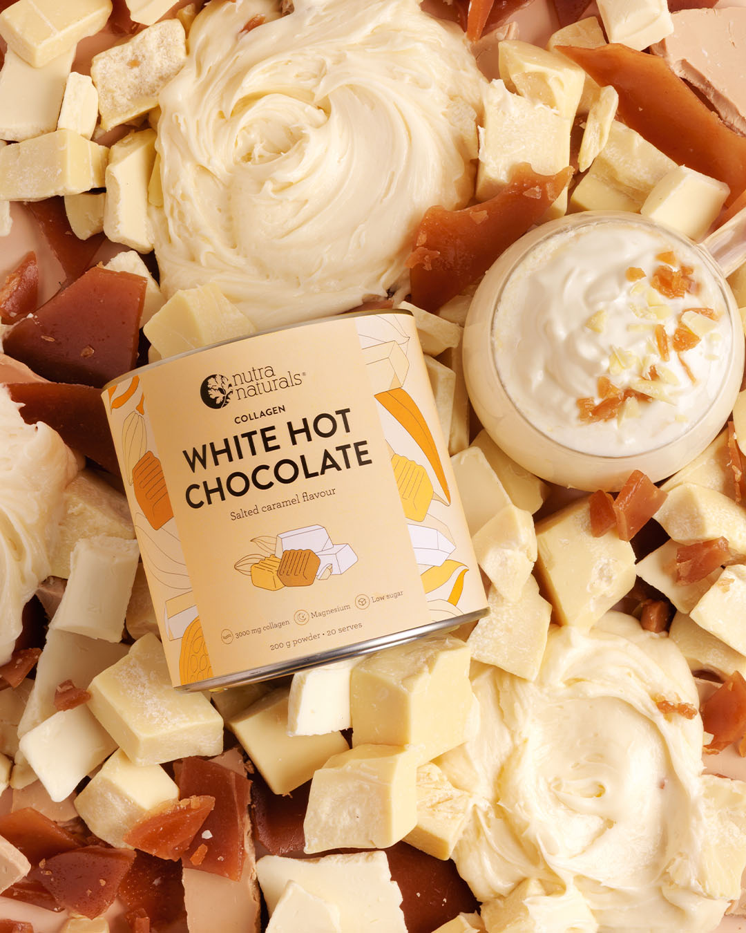 Can of white hot chocolate surrounded by white chocolate pieces and cream.